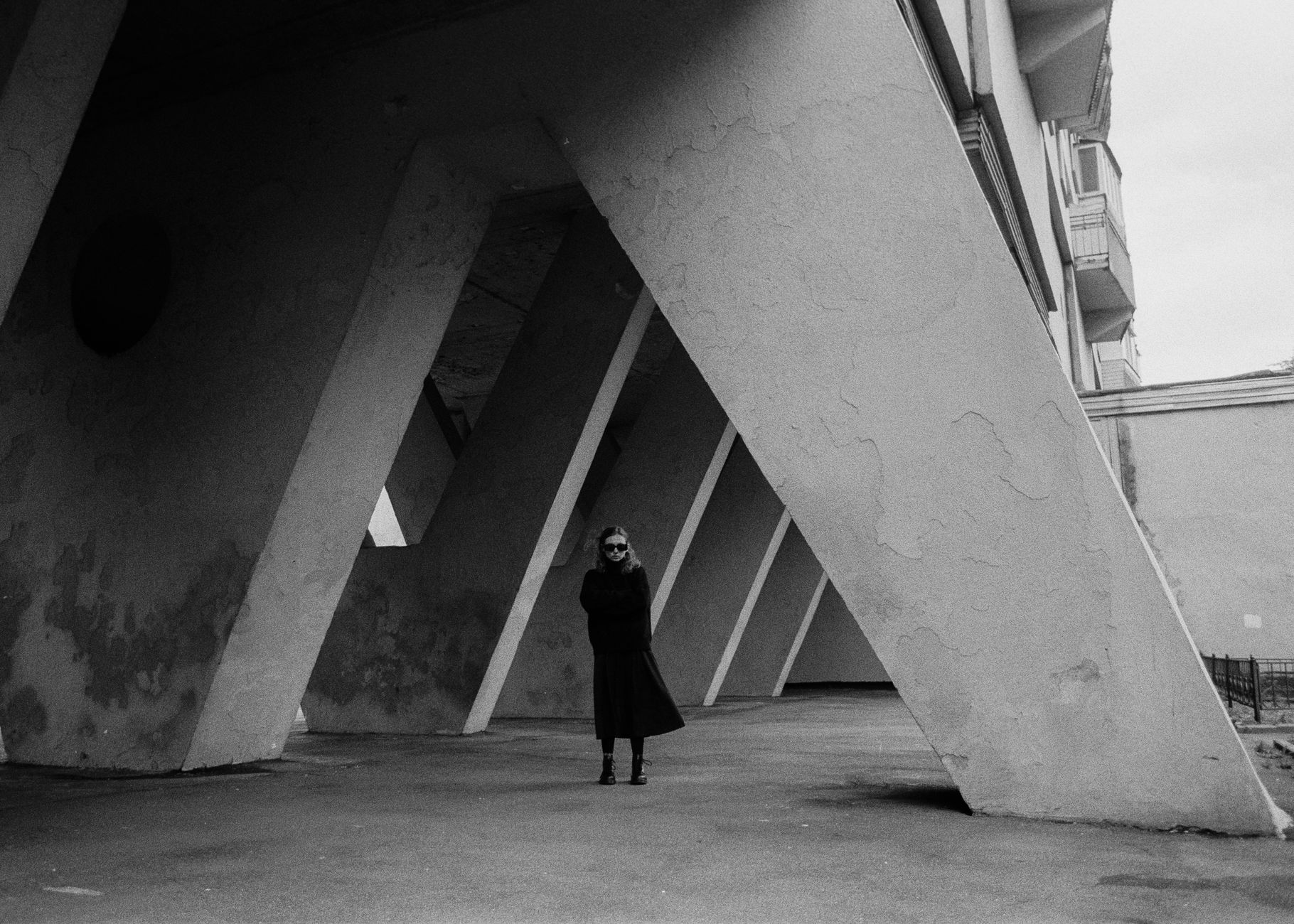 Fashion model wearing an oversized coat against contemporary architecture